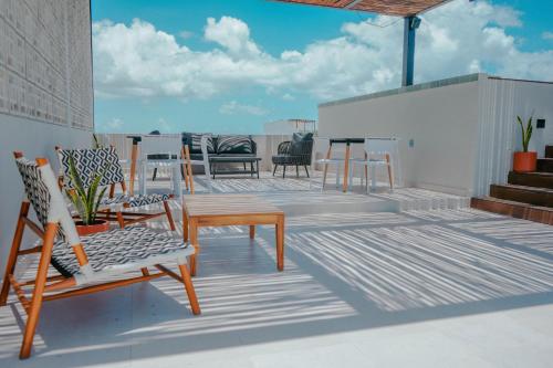 a patio with chairs and tables on a roof at Macondo Quinta Avenida Residences in Playa del Carmen