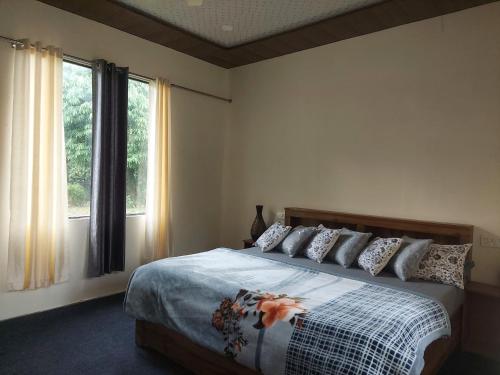 a bedroom with a bed and a large window at The River Sound Cottages in Ukhimath