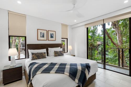 a bedroom with a large bed and large windows at Vista Verde - A Temple Resort Family Treasure in Palm Cove