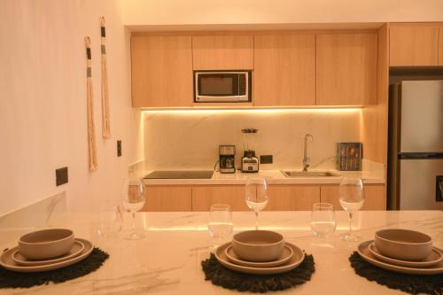 a kitchen with a table with plates and wine glasses at Macondo Quinta Avenida Residences in Playa del Carmen