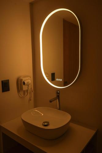 a bathroom with a sink with a round mirror at Macondo Quinta Avenida Residences in Playa del Carmen