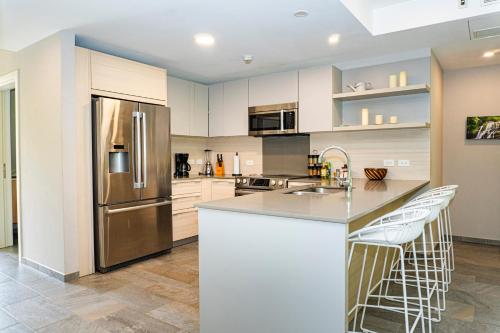 a kitchen with a stainless steel refrigerator and white cabinets at Elan at Ballena Beach in Uvita