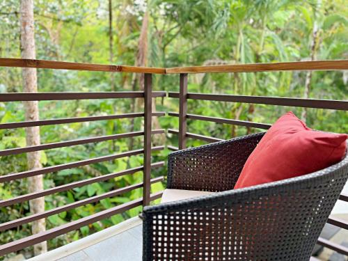 a wicker chair with a red pillow on a balcony at Elan at Ballena Beach in Uvita