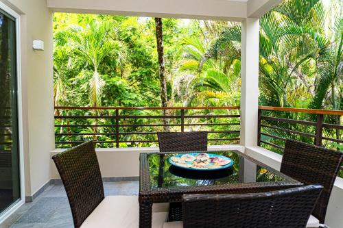 a balcony with a table and chairs and trees at Elan at Ballena Beach in Uvita