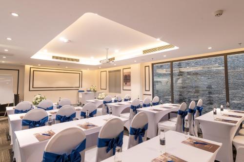 a conference room with white tables and blue chairs at FTE Ba Dinh Hotel in Hanoi