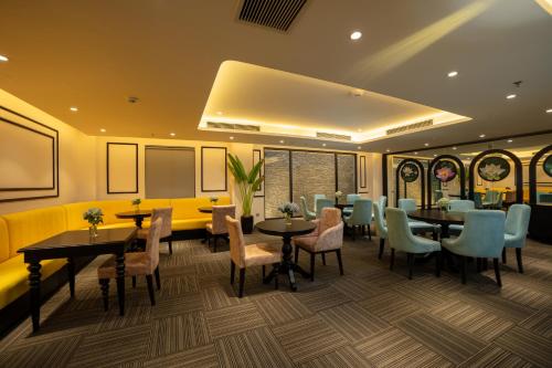 a restaurant with tables and chairs and a yellow couch at FTE Ba Dinh Hotel in Hanoi