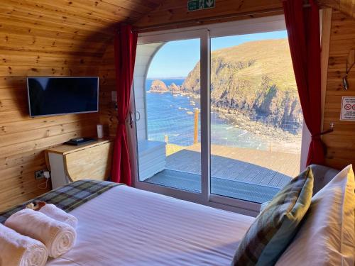 a bedroom with a large window with a view of the ocean at SEApods - Isle of Lewis - Luxury en-suite pods on the edge of the Atlantic Ocean in Aird Uig