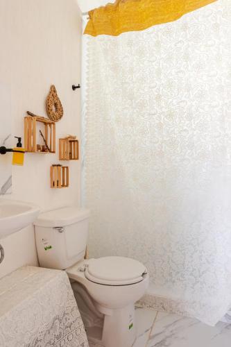 a bathroom with a toilet and a shower curtain at Hippie Artisan Jungle Flat Pool in Tulum