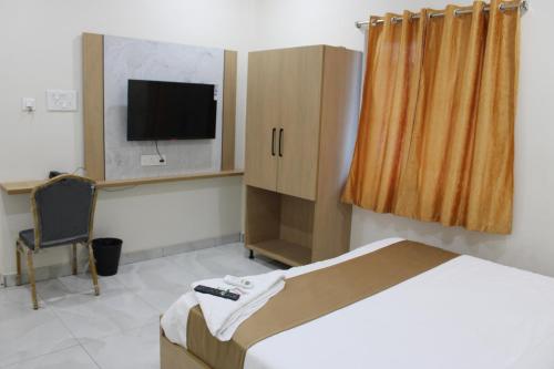 a bedroom with a bed and a tv and a chair at Hotel Vaarahi Chanda Nagar, Near Hitech City in Hyderabad