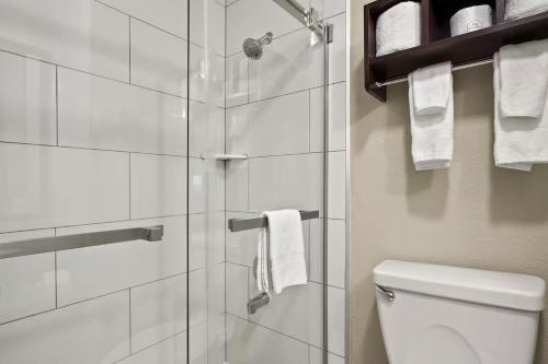 a bathroom with a shower and a toilet and towels at Baymont by Wyndham Henderson-Northeast Denver in Henderson