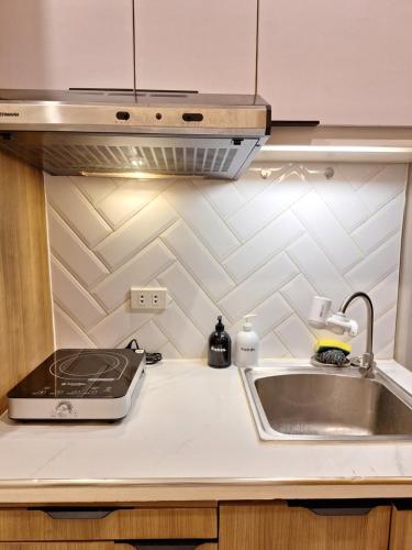 a kitchen counter with a sink and a stove at Sky Lux Suite by Elnora at Victoria Sports Tower Kamuning Edsa Southbound in Manila