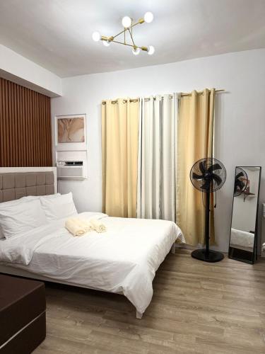 a bedroom with a bed with white sheets and a fan at Willow Nest in Bacolod