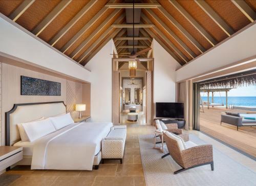 a bedroom with a bed and a living room at Waldorf Astoria Maldives Ithaafushi in South Male Atoll