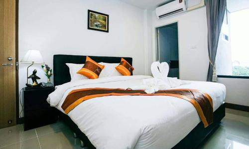 a bedroom with a large bed with orange and white pillows at Noble Boutique Hotel Chiang Mai By J&S Property in Chiang Mai