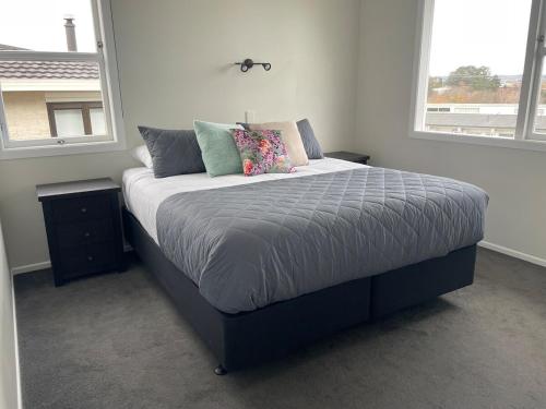 a bed in a bedroom with two windows at The Lake House in Taupo