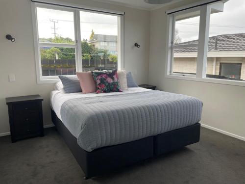 a bedroom with a large bed with two windows at The Lake House in Taupo