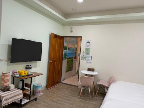 a bedroom with a bed and a tv on the wall at Yu Shou Hao Hsien Guesthouse in Fushi