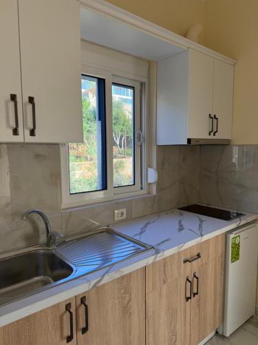 a kitchen with white cabinets and a sink and a window at Villa Evelyn Free Parking in Vlorë