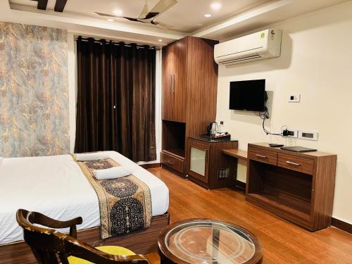 瓦拉纳西Trimrooms Banaras Station的配有床、书桌和电视的酒店房间