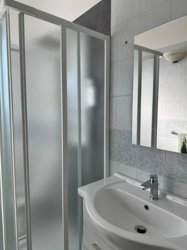 a white bathroom with a sink and a mirror at Borgata Lu Fraili in Nuragheddu