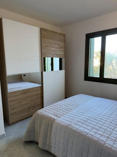 a bedroom with a bed and a large window at Borgata Lu Fraili in Nuragheddu