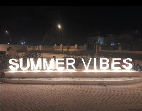a large sign that says summer vibes on a sidewalk at night at شاليه ديمورا عائلات فقط Dimora Chalet Only Family in Dawwār Muḩammad Abū Shunaynah