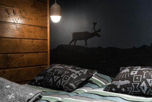 a bedroom with a bed with pillows and a deer on the wall at Tundrea Holiday Resort in Kilpisjärvi