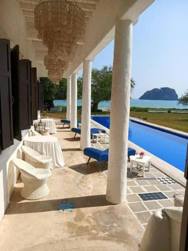 a patio with tables and chairs and a pool at Brassiere Beach Hotel in Baanphakrimlay 