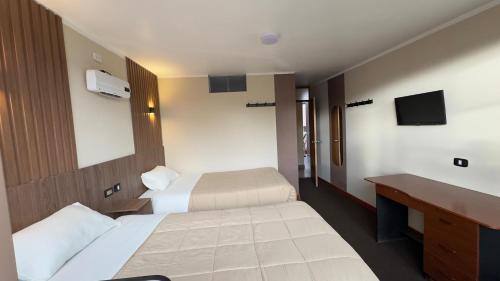 a hotel room with two beds and a desk at Hotel Posada de Belén in Espinar