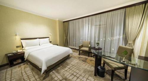 a hotel room with a bed and a desk and a window at Jincheng Pacific Hotel in Jincheng