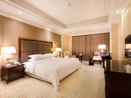 a large bedroom with a large bed and a desk at Jinjiang Grandlink Hotel in Quanzhou