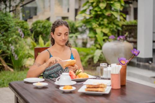 a woman sitting at a table eating food at Wasantha Garden Hotel Restaurant & Ayurvedic Treatment in Weligama
