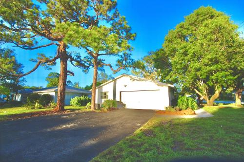 a house with a white garage and two trees at Coastal Village Retreat in Jupiter