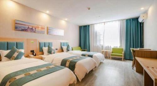 a hotel room with three beds and a desk at Lijiang Waika Hotel in Lijiang