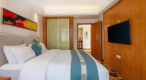 a bedroom with a large bed and a flat screen tv at Lijiang Waika Hotel in Lijiang