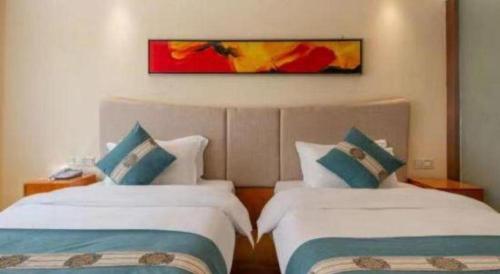 a hotel room with two beds and a painting on the wall at Lijiang Waika Hotel in Lijiang