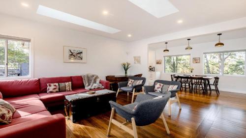 a living room with a red couch and chairs at Bush Setting With Easy Walk To Beach in Macmasters Beach