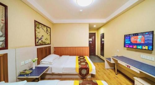 a hotel room with a large bed and a flat screen tv at Kunlun Leju Business Hotel Kaifeng Gulou in Kaifeng