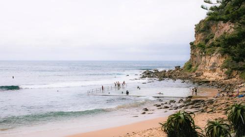 a group of people on a beach near the ocean at Bush Setting With Easy Walk To Beach in Macmasters Beach