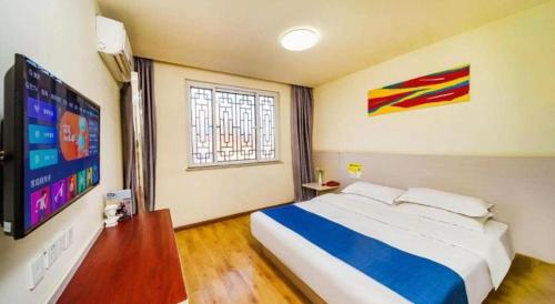 a bedroom with a large bed and a flat screen tv at Kunlun Leju Business Hotel Kaifeng Gulou in Kaifeng