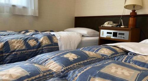 a room with three beds with blue and white blankets at Hotel Town Nishikigawa in Kochi