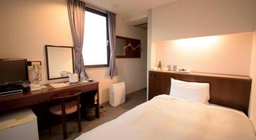 a bedroom with a bed and a desk with a computer at Hotel Matsuya in Shimanto