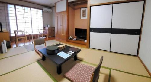 a living room with a table and chairs and a room at Kirishima Onsen Ryokojin Sanso in Kirishima
