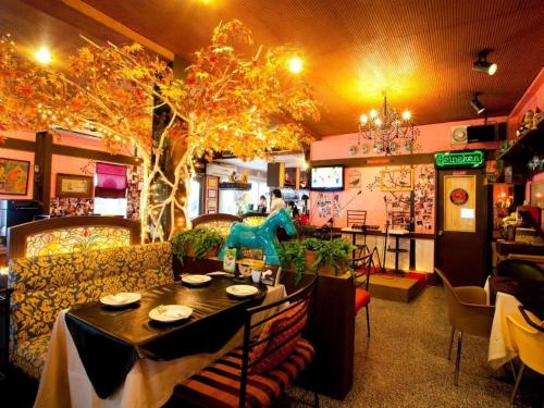 a restaurant with a table and chairs and a tree at Numsin Hotel in Ratchaburi