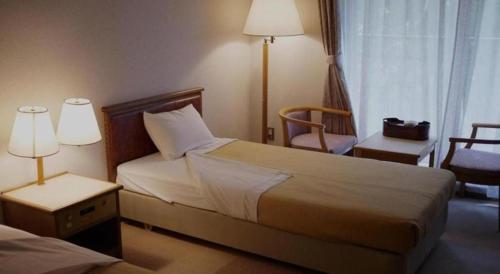 a hotel room with two beds and a chair at Otaiko Hills in Fukui