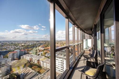 una mujer sentada en una silla en el balcón de un edificio en South Yarra 2 Bed with Superb views - 4 Day Minimum, en Melbourne