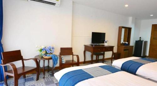 a bedroom with two beds and a desk and a television at The Indigo House Phrae in Phrae