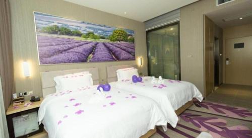 a bedroom with two beds and a painting on the wall at Lavande Hotel Yichang Railway East Station Branch in Yichang