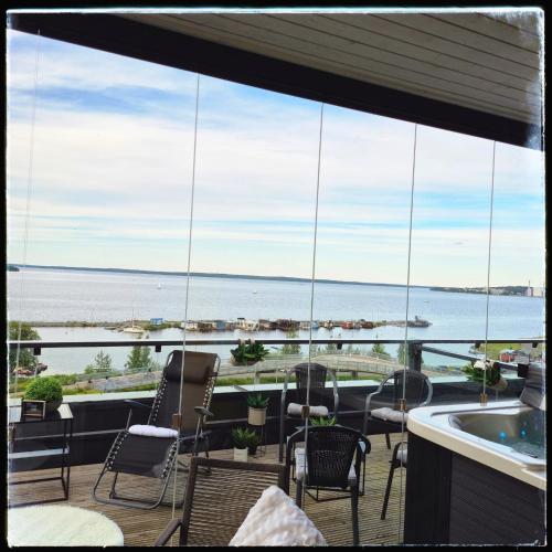 a balcony with chairs and a view of the water at TAMPERE PENTHOUSE-tasokas moderni kaupunki huoneisto huipulla -ISO JACUZZI omalla KATTOTERASSILLA - AURINKOTUOLIT ja Aurinko odottaa Sinua - huikea maisema- - 10 HLÖ - free parking in Tampere
