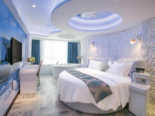 a bedroom with a large white bed and a tub at Vienna Hotel - Shenzhen Dongmen Hubei Metro Station in Shenzhen
